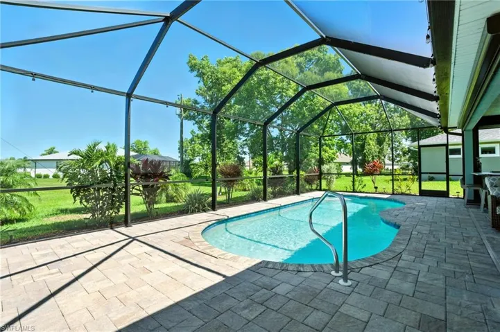 Swimming pool featuring a sunroom, glass enclosure, a lawn, and a patio