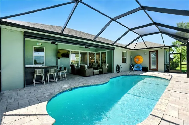 Rear view of house featuring roof with shingles, outdoor lounge area, a sunroom, a lanai, and stucco siding