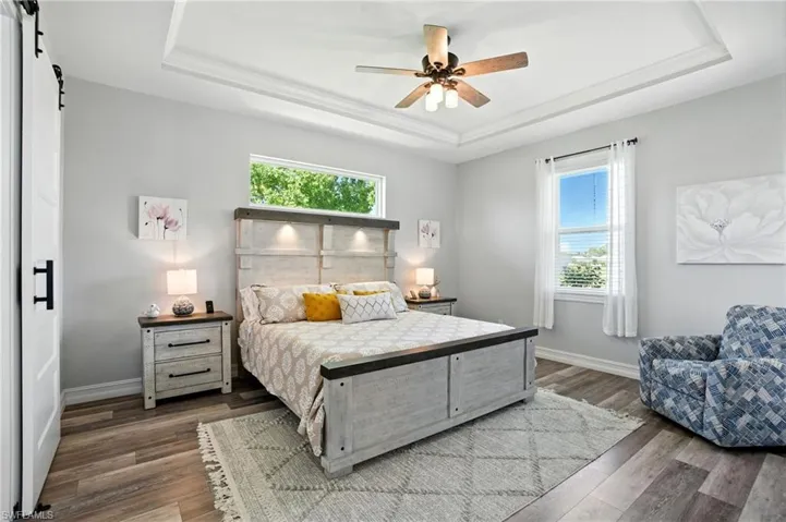 Bedroom featuring a raised ceiling, a barn door, and multiple windows