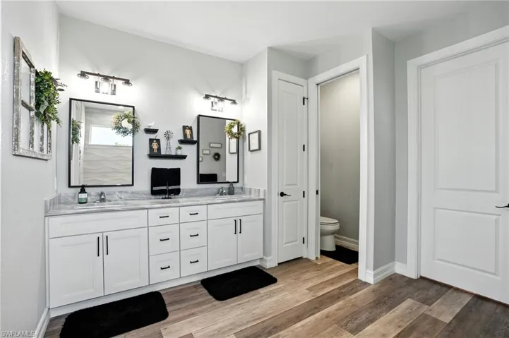 Bathroom with double vanity and light wood-style flooring