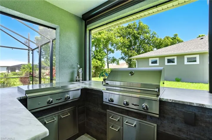 View of patio / terrace with a sunroom, an outdoor kitchen, and a lanai