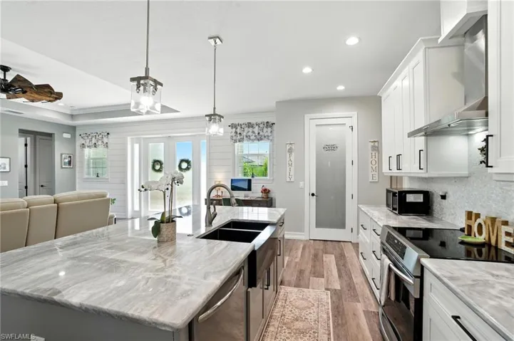 Kitchen with white cabinetry, stainless steel appliances, open floor plan, recessed lighting, and light wood-style floors