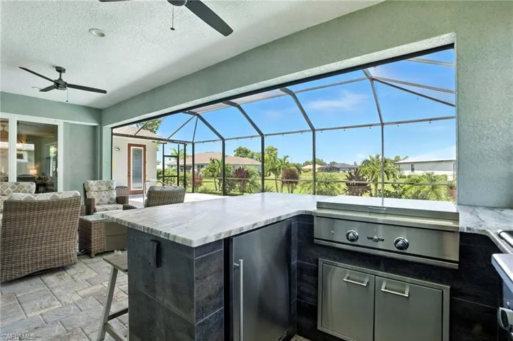 View of patio / terrace with exterior kitchen, a sunroom, a ceiling fan, an outdoor hangout area, and a lanai