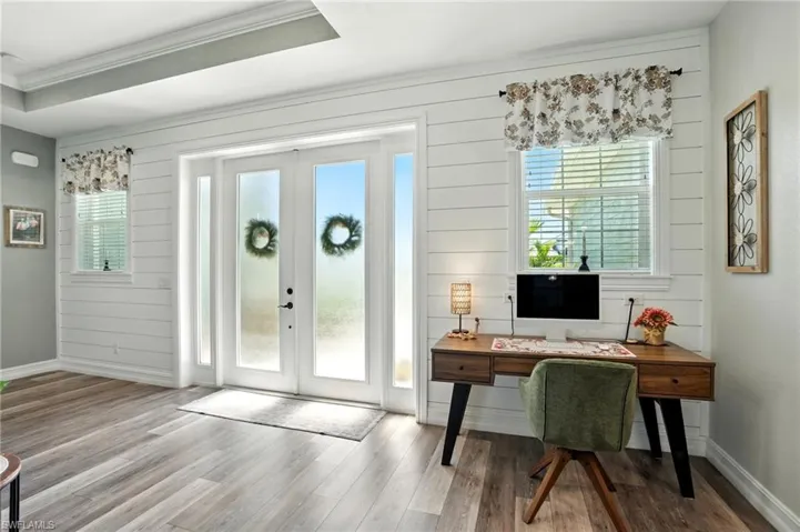 Entryway featuring french doors, wood finished floors, wooden walls, crown molding, and a desk