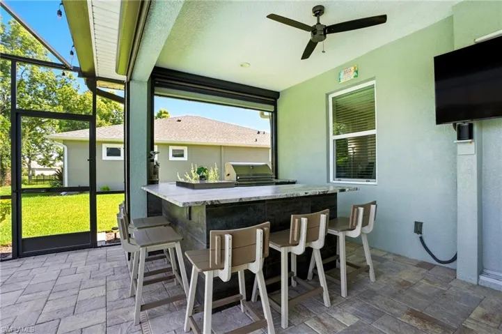 View of patio with a sunroom, a lanai, exterior kitchen, and a ceiling fan
