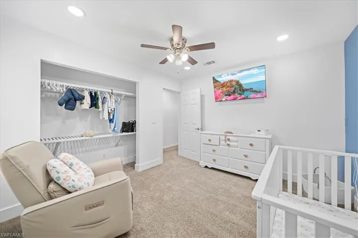 Bedroom with a crib, light colored carpet, a closet, ceiling fan, and recessed lighting