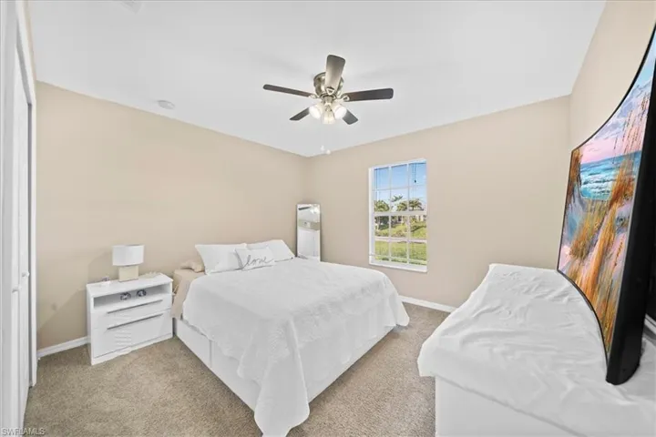 Carpeted bedroom featuring baseboards and ceiling fan