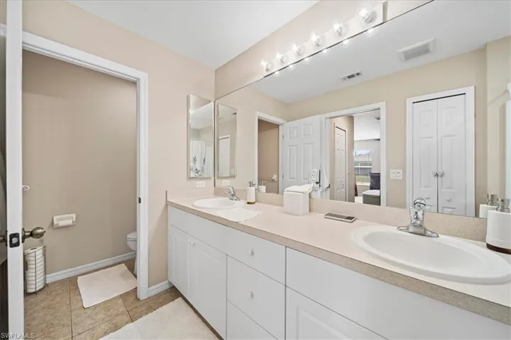 Full bathroom featuring a closet, double vanity, and light tile patterned floors