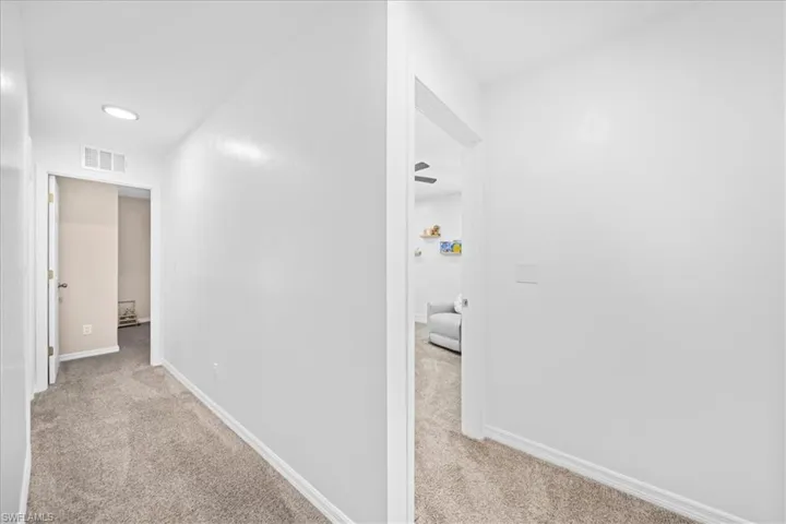 Corridor featuring light carpet