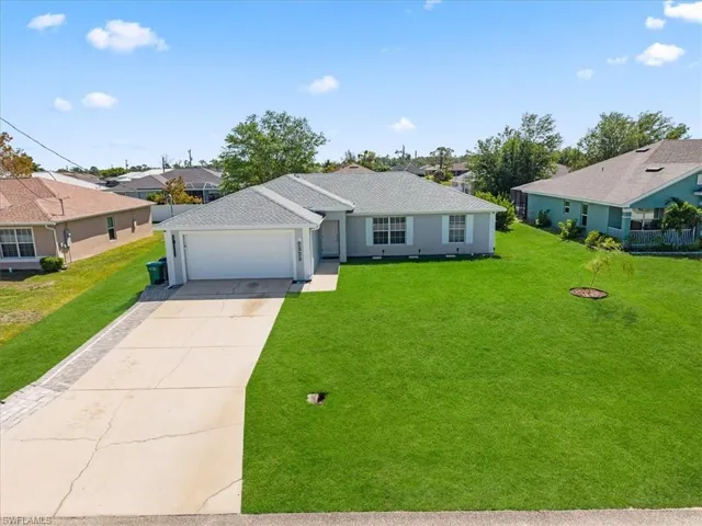 Single story home featuring a front yard, driveway, a residential view, and a garage
