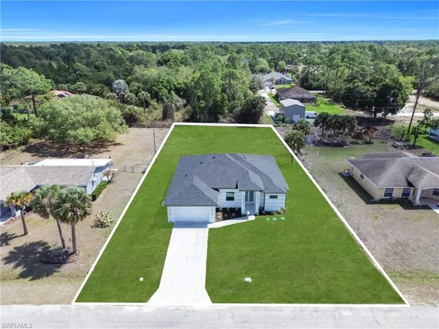 Aerial view of residential area featuring property boundaries highlighted and a forest