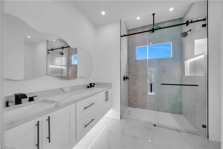Full bathroom with a marble finish shower, double vanity, and recessed lighting