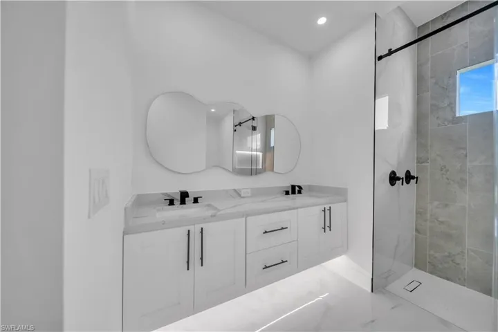 Full bathroom featuring a walk in shower, double vanity, and recessed lighting