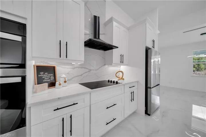 Kitchen featuring stainless steel appliances, light stone countertops, white cabinets, and tasteful backsplash