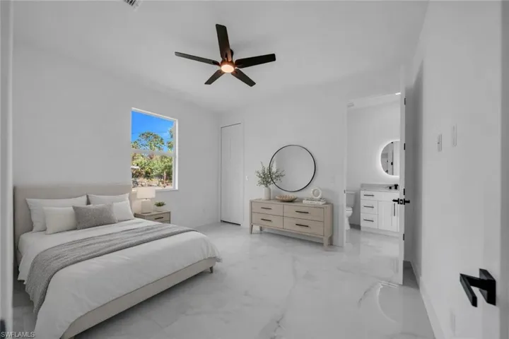 Bedroom featuring ceiling fan, light marble finish floors, and connected bathroom