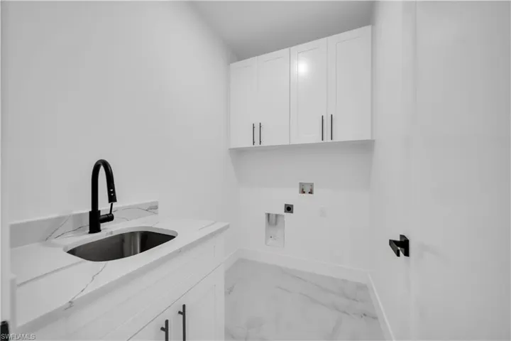 Laundry area featuring cabinet space, washer hookup, light marble finish flooring, and electric dryer hookup