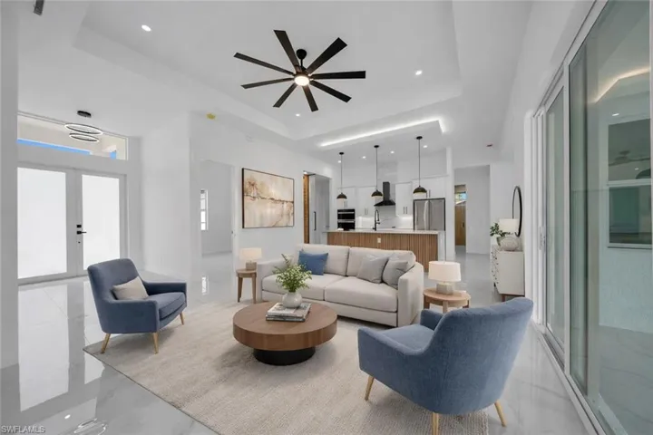 Living area with a raised ceiling, ceiling fan, and recessed lighting