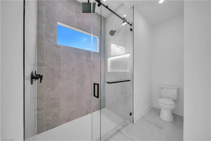 Full bath featuring a marble finish shower and marble finish flooring