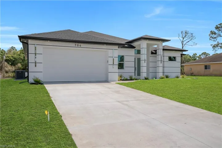 Prairie-style home with a shingled roof, a front lawn, driveway, and an attached garage