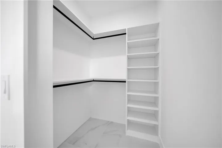Walk in closet featuring light marble finish flooring