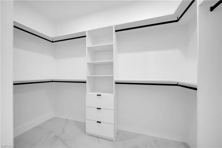 Walk in closet with light marble finish floors