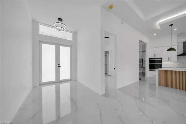 Foyer entrance featuring french doors and light marble finish floors