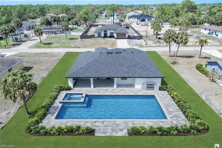 Integrated pool / spa featuring a patio area, a lawn, an outdoor kitchen, and a residential view
