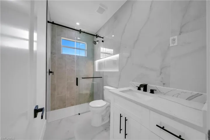 Full bathroom with vanity, a shower stall, and light marble finish flooring