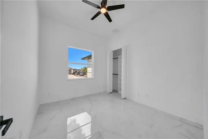 Unfurnished bedroom featuring light marble finish flooring, ceiling fan, and a closet