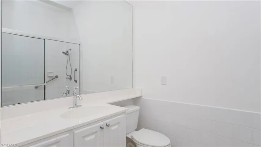 Bathroom featuring tile walls, vanity, toilet, and an enclosed shower