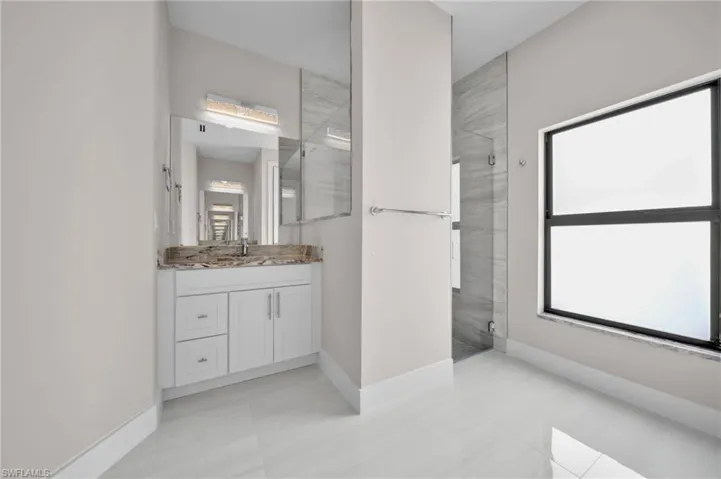 Full bathroom featuring vanity, plenty of natural light, a shower with door, and baseboards