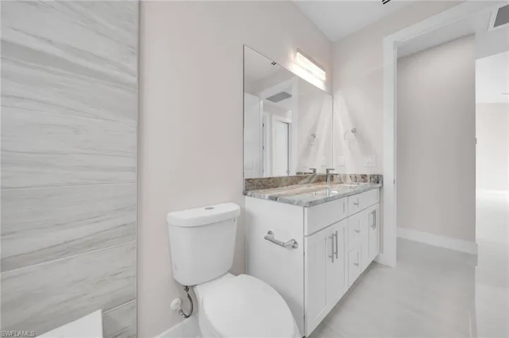 Bathroom featuring vanity, toilet, and baseboards