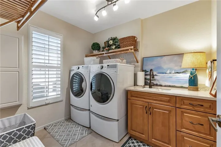 Laundry room with cabinet space, washer and dryer, and light tile patterned floors
