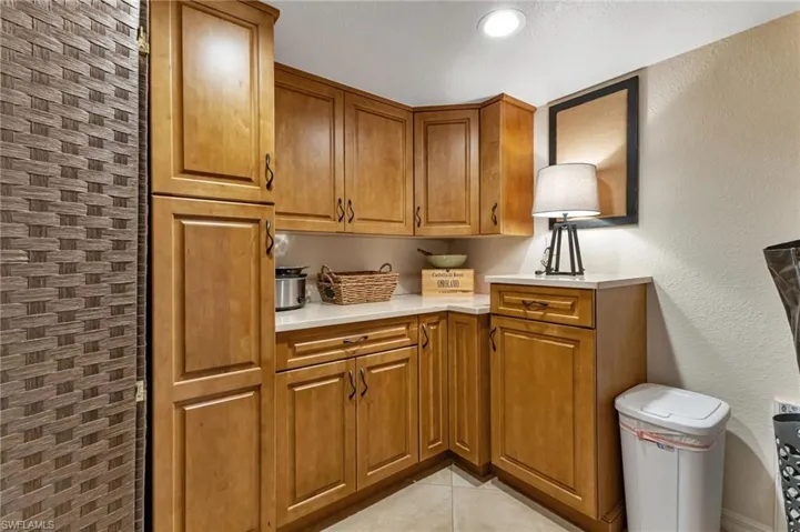 Kitchen featuring a textured wall, wood finish cabinetry, and light tile patterned flooring
