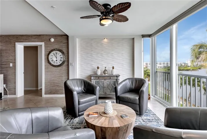 Tiled living room with ceiling fan and expansive windows