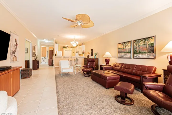 Living area with crown molding, light tile patterned floors, a chandelier, and ceiling fan