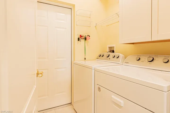 Washroom featuring separate washer and dryer, cabinet space, and light tile patterned flooring