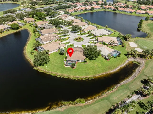 Aerial view of property and surrounding area featuring nearby suburban area, a nearby body of water, and a golf course