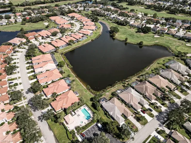 Aerial view of property and surrounding area featuring nearby suburban area and a golf course