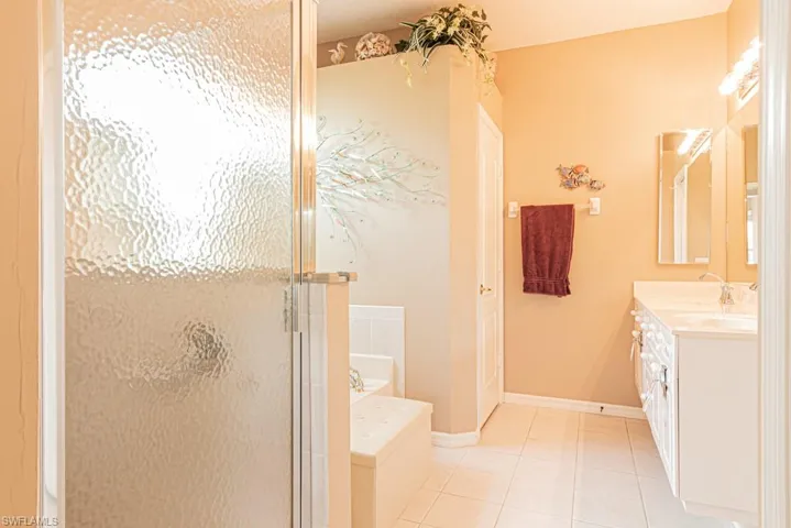 Full bath with double vanity, tile patterned floors, a garden tub, and a shower stall