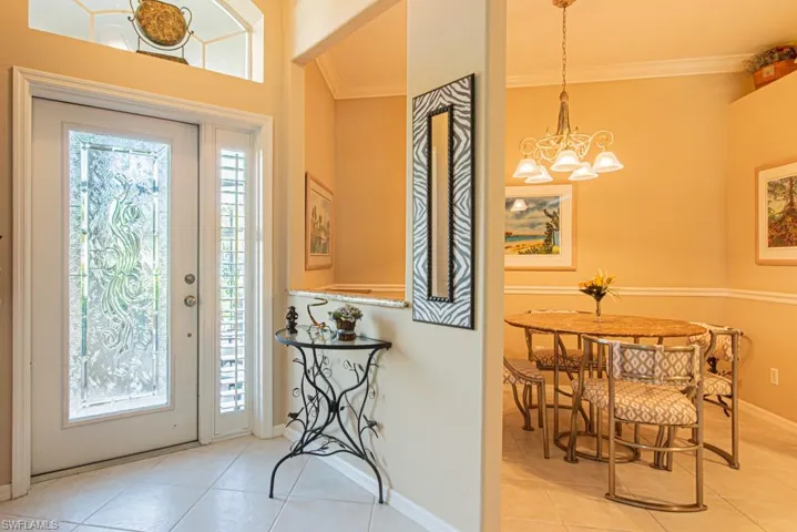 Foyer featuring tile patterned floors, ornamental molding, and a chandelier