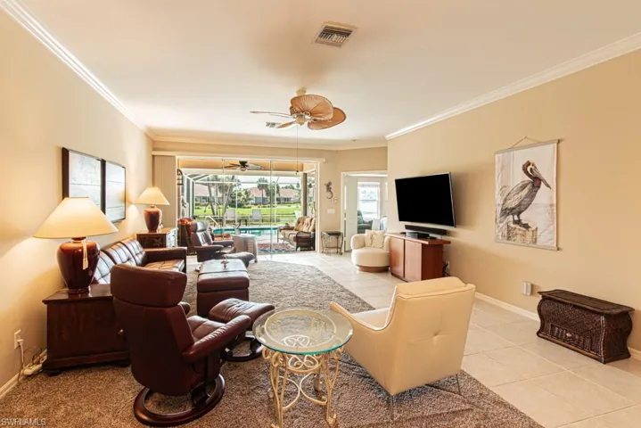 Living room featuring tile patterned floors, ceiling fan, and ornamental molding