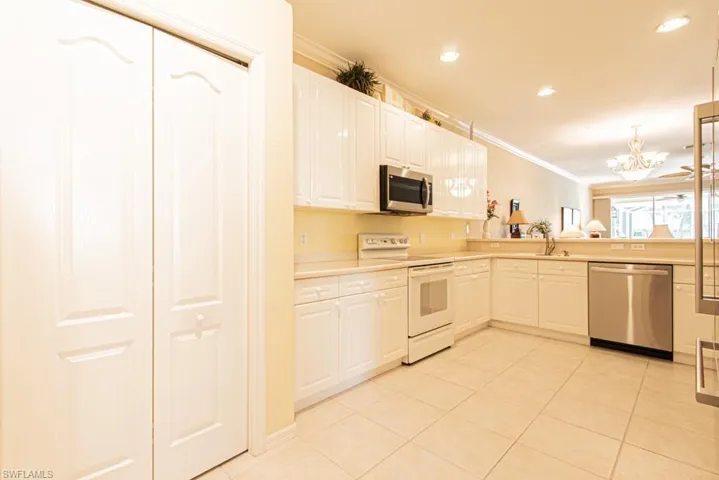 Kitchen featuring stainless steel appliances, ornamental molding, light tile patterned flooring, light countertops, and a chandelier