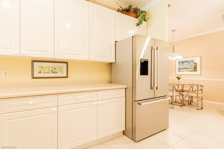 Kitchen featuring ornamental molding, high end fridge, light tile patterned floors, white cabinetry, and a chandelier