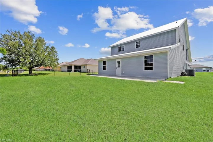 Rear view of house with a patio area and a lawn