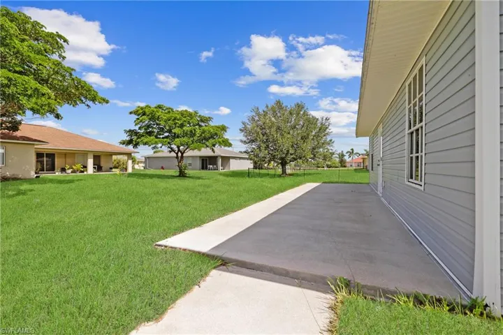 View of grassy yard featuring a patio area