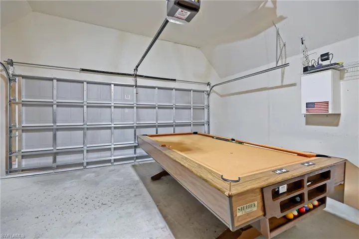 Rec room with a garage, unfinished concrete flooring, and billiards