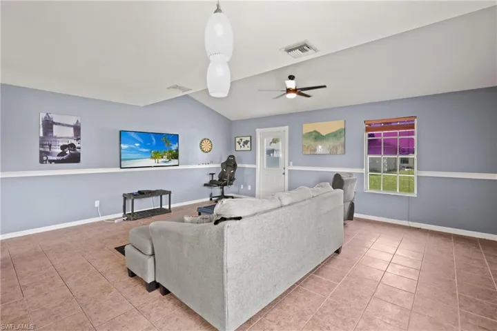 Tiled living area with lofted ceiling and a ceiling fan