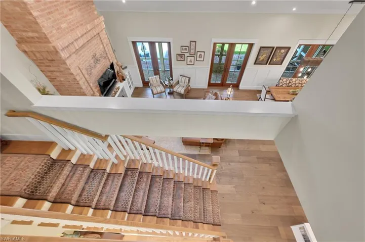 Open staircase with hardwood treads and railings overlooks the great room below, creating a seamless connection between levels and enhancing the home's spacious, light-filled design