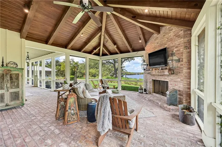 This outdoor living room features vaulted, beamed, wood ceilings, brick flooring and gas fireplace